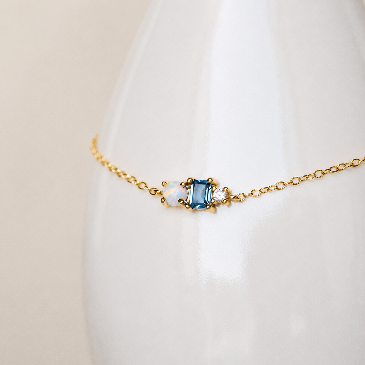 Gold necklace with a blue gemstone on a white background